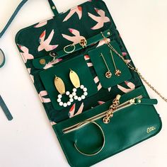 a green purse filled with jewelry on top of a white table next to a pair of scissors