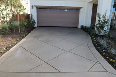 a house with a driveway in front of it and flowers on the ground next to it