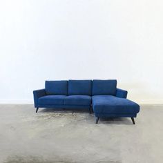 a blue couch sitting on top of a cement floor next to a white wall in an empty room