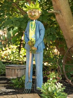 a scarecrow is standing in front of a tree and holding a fork with his head