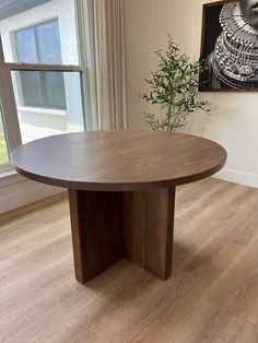 a round wooden table sitting in front of a window