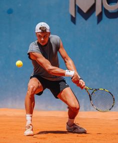 a man holding a tennis racquet on top of a tennis court with a ball in the air