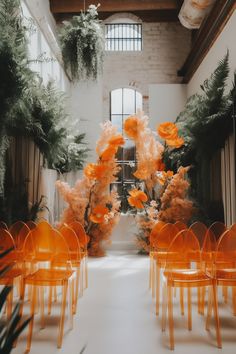 orange chairs are lined up in the middle of an indoor space with flowers and greenery