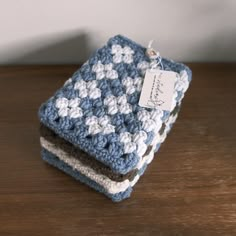 two blue and white crocheted dishcloths sitting on top of a wooden table