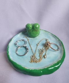 a green tray with rings and necklaces on it