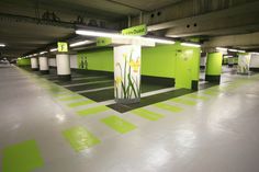 an empty parking garage with green and white painted walls, flooring and lights on the ceiling