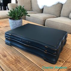 a large black suitcase sitting on top of a wooden table next to a couch and potted plant