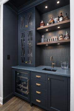 a kitchen with dark blue cabinets and gold pulls on the cupboards, along with glass shelves