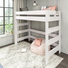 a white bunk bed sitting on top of a rug in a bedroom next to a window