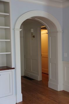 an archway leads to the living room and dining room in this house, with hardwood floors