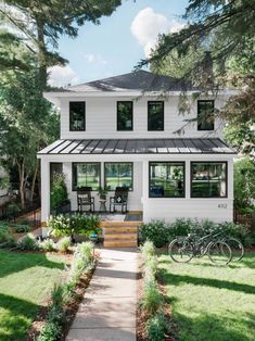 a white house with a black roof and two bikes parked in front of the door