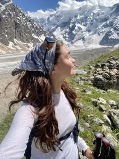 a woman standing on top of a lush green field next to mountains covered in snow