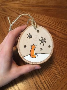 a hand holding a wooden ornament with a fox on it