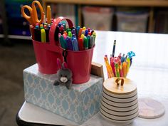 there are many pens and pencils in the cup on the table next to each other