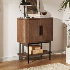 a wooden cabinet sitting on top of a hard wood floor next to a potted plant