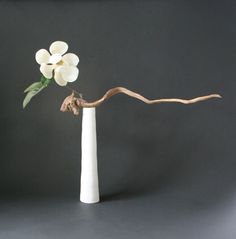 a white vase with a branch and flowers in it