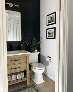 a white toilet sitting next to a wooden sink vanity in a bathroom under a mirror