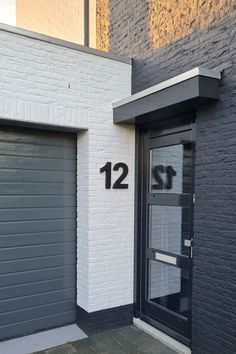 two garage doors with numbers on them in front of a brick building