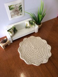 a crocheted rug sits on the floor next to a couch and potted plant