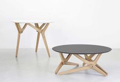 two round tables with wooden legs and black top sitting on a white floor next to each other