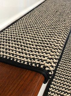 a black and white rug sitting on top of a wooden floor next to a wall