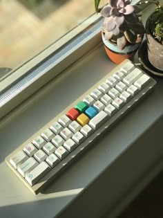 a keyboard sitting on top of a window sill next to a potted plant