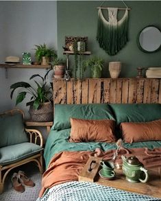 a bed with green sheets and pillows in a room filled with potted plants on top of it