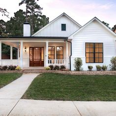 a white house with black trim and two windows on the front porch is shown at dusk