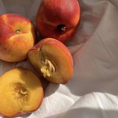 three peaches cut in half on a white cloth