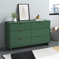 a green dresser sitting in a room next to a window with a potted plant on top