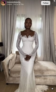 a woman in a white wedding dress standing next to a couch