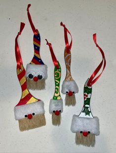 three christmas ornaments hanging from red ribbon on a white table with silver and gold trim