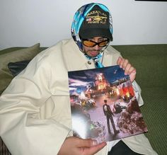 a man sitting on top of a couch holding up a photo with his face covered