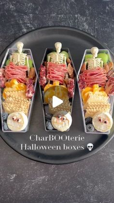 three trays filled with halloween treats on top of a black table next to each other