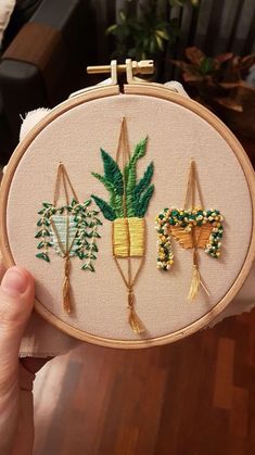 a person holding up a small embroidery project