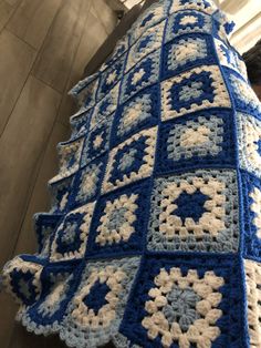 a blue and white crocheted blanket hanging from the side of a wall next to a window