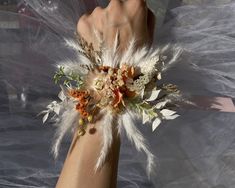 a woman's arm with flowers and feathers attached to it, on top of sheer fabric