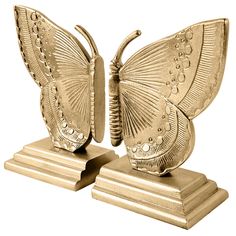 two gold butterfly figurines sitting on top of each other's bases,