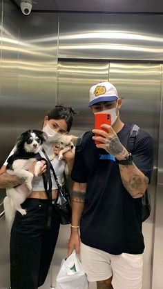 two people taking pictures with their dogs in an elevator