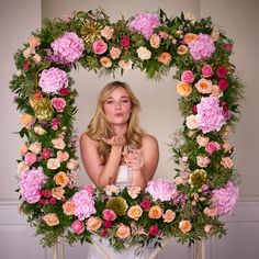 a woman standing in front of a floral wreath