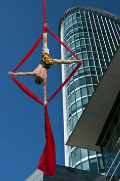 a man is performing aerial acrobatic tricks in front of a tall building