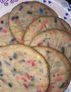 three cookies with sprinkles on a plate