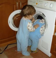 a young child standing in front of a washing machine