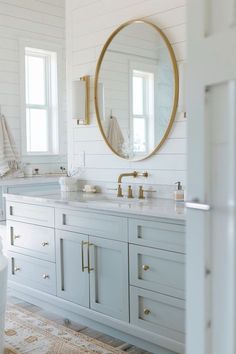 a bathroom with two sinks and a large round mirror on the wall above it's counter