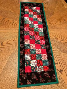 a table runner made out of quilts on top of a wooden table with a green border