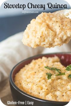 a spoonful of mashed potatoes with herbs in a black bowl on a wooden table