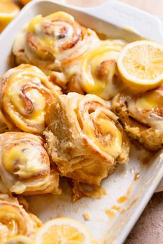 lemon rolls in a baking dish with sliced lemons