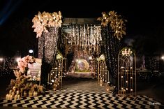 an outdoor wedding setup with lights and flowers on the aisle, decorated in black and white