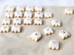 cookies with white icing and ghost faces are arranged on a baking sheet