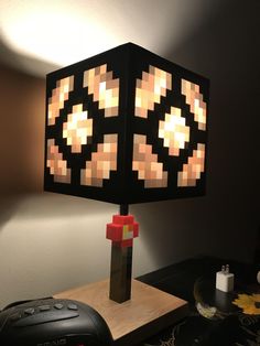 a lamp that is on top of a wooden table next to a remote control and controller